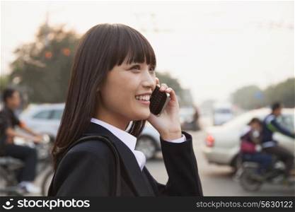 Young businesswoman using the phone outside on the street in Beijing