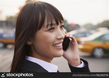 Young businesswoman using the phone outside on the street in Beijing, close up portrait