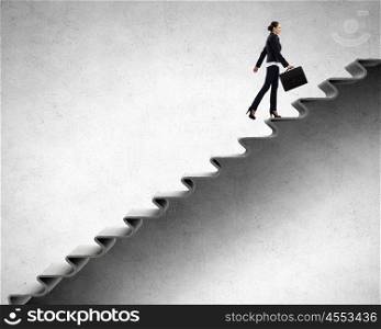 Young businesswoman walking up on staircase representing success concept. Up the career ladder