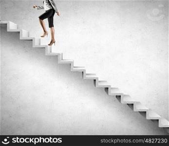 Young businesswoman walking up on staircase representing success concept. Up the career ladder