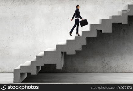 Young businesswoman walking up on staircase representing success concept. Up the career ladder