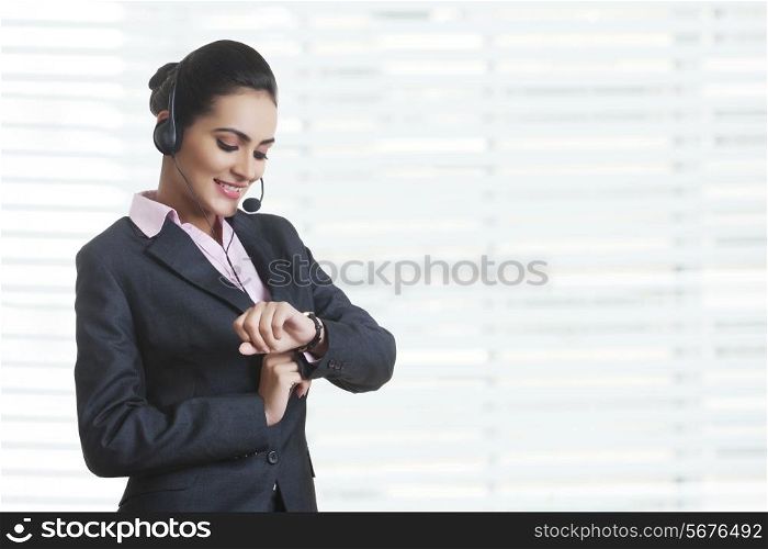 Young businesswoman wearing headset while checking time at office