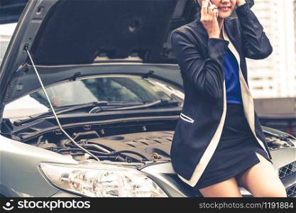 Young businesswoman whose car breakdown uses mobile phone to call for roadside assistance service. Travel and transportation vehicle problem.