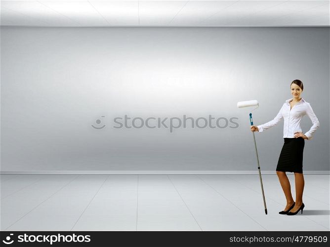 Young businesswoman with a paint brush against white wall