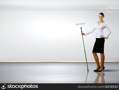 Young businesswoman with a paint brush against white wall
