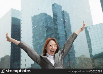 Young businesswoman with arms outstretched among skyscrapers, Beijing
