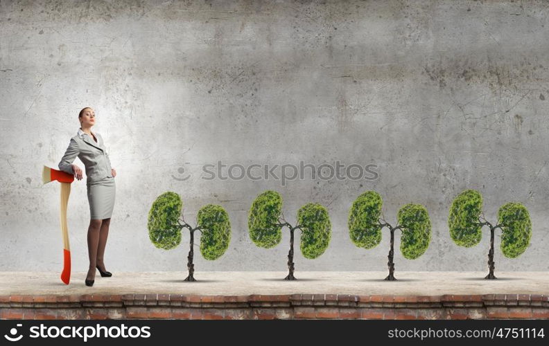 Young businesswoman with axe and green tree. Deforestation problem