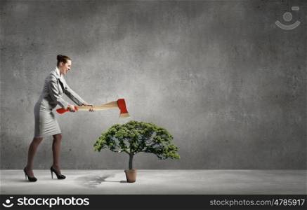 Young businesswoman with axe and green tree. Deforestation problem