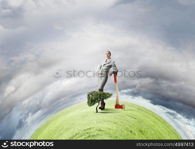 Young businesswoman with axe and green tree. Deforestation problem