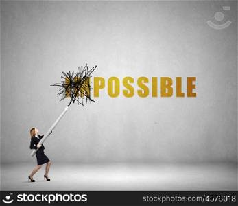 Young businesswoman with huge pencil changing word impossible. Nothing is impossible