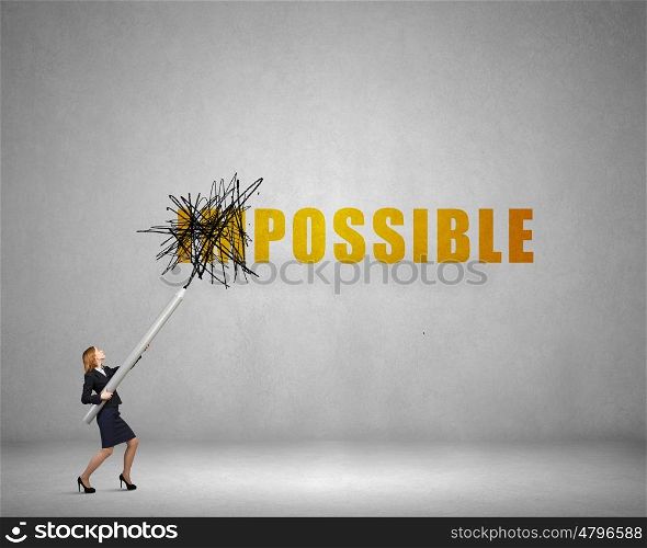 Young businesswoman with huge pencil changing word impossible. Nothing is impossible