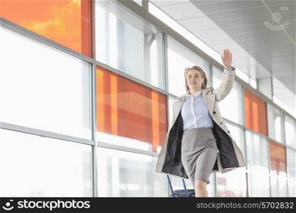 Young businesswoman with luggage running in railroad station