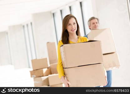 Young businesswoman with male colleague carrying cardboard boxes in new office