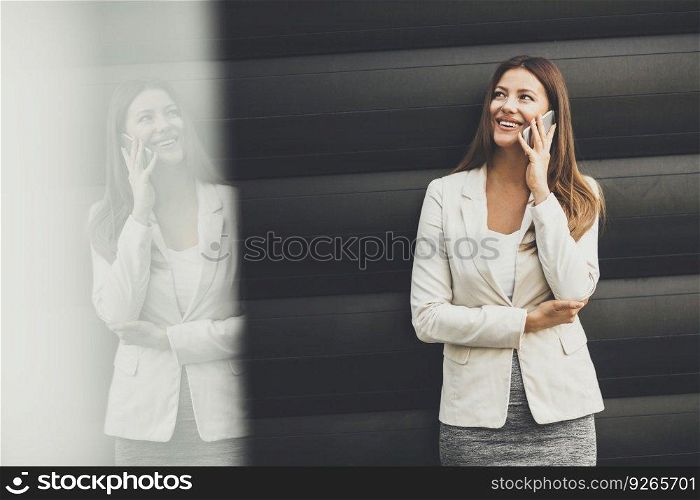 Young  businesswoman with mobile phone in front of office building