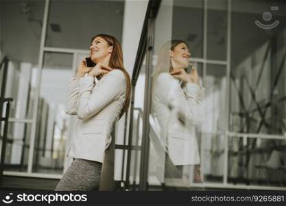 Young businesswoman with mobile phone in front of office building