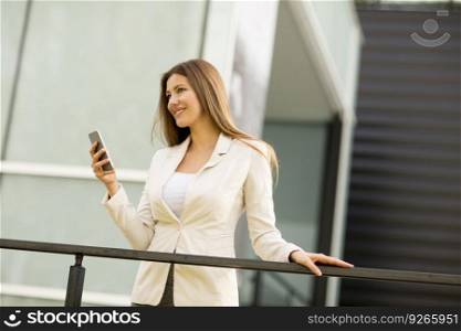 Young  businesswoman with mobile phone in front of office building