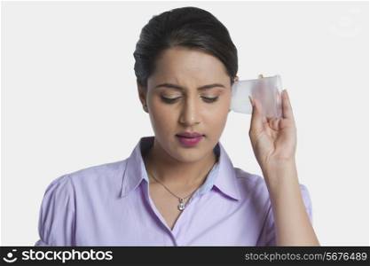 Young businesswoman with plastic glass on ear over white background