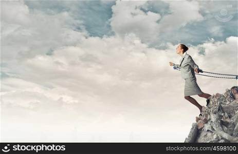 Young businesswoman with ropes on hands trying to fly. Roped businesswoman