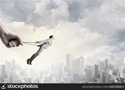 Young businesswoman with ropes on hands trying to fly. Roped businesswoman