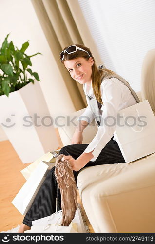 Young businesswoman with shopping bag on sofa, plant in background