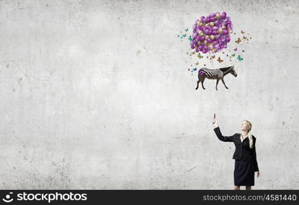 Young businesswoman with suitcase and bunch of colorful balloons. Taking break from business