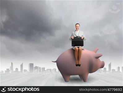 Young businesswoman with suitcase in hand sitting on piggybank. Woman on moneybox