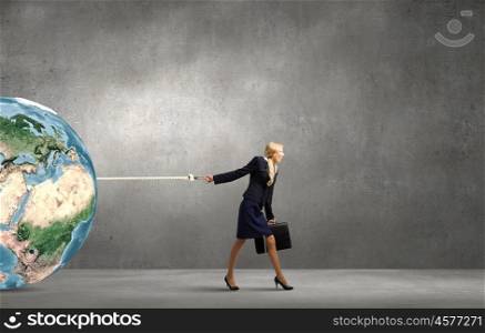 Young businesswoman with suitcase pulling Earth planet with lead. Elements of this image are furnished by NASA. The world is mine