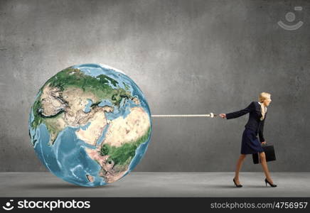 Young businesswoman with suitcase pulling Earth planet with lead. Elements of this image are furnished by NASA. The world is mine