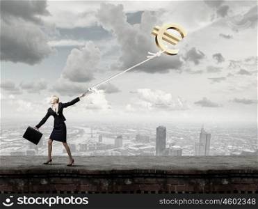 Young businesswoman with suitcase pulling euro sign on lead. Euro currency