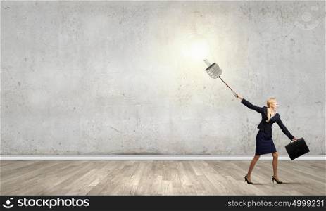 Young businesswoman with suitcase pulling light bulb on lead. Idea concept