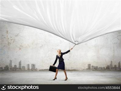 Young businesswoman with suitcase pulling white blank banner. Place for your text