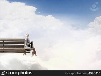 Young businesswoman with suitcase sitting on bench. Taking break from office
