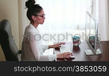 Young businesswoman working on her computer in the office.Writing an email clicking the keyboard and mouse.A clerk emailing a corporate letter and chatting.