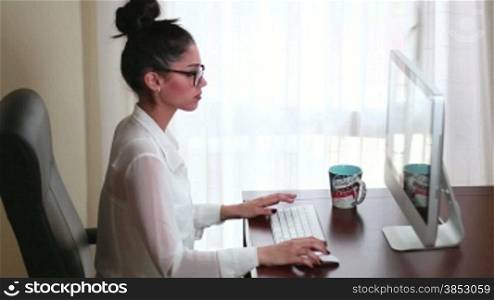 Young businesswoman working on her computer in the office.Writing an email clicking the keyboard and mouse.A clerk emailing a corporate letter and chatting.