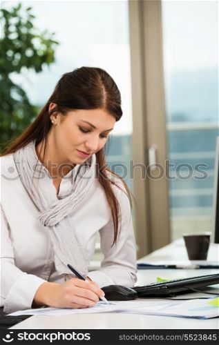 Young businesswoman writing at office desk