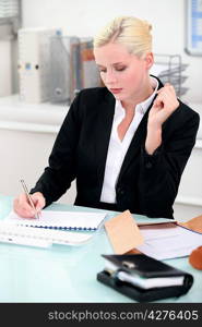 Young businesswoman writing notes at her desk