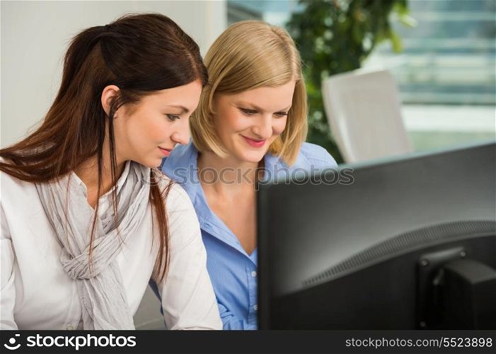 Young businesswomen looking at computer monitor in office