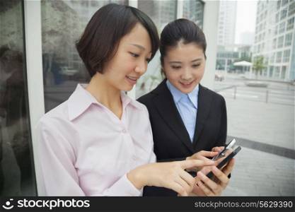 Young businesswomen looking at their cell phones