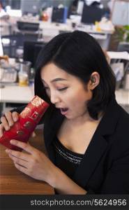 Young businesswomen looking into traditional red envelopment, Chinese New Year