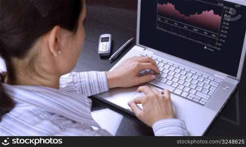 Young businesswomen works on a laptop computer and reads financial analyses.