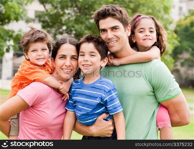 Young cacuasian parents piggyback their children as they smile at camera