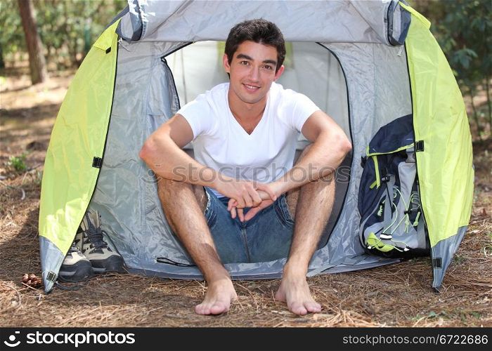 young camper posing near tent