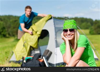 Young camping couple build-up tent in summer meadows countryside