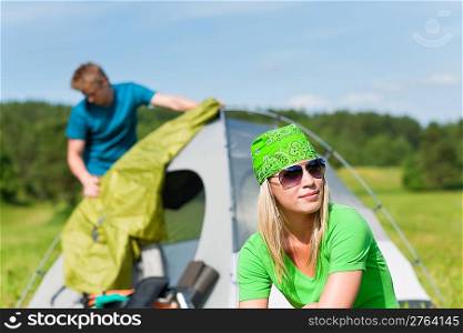 Young camping couple build-up tent in summer meadows countryside