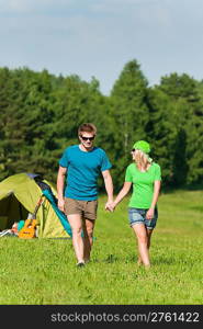 Young camping couple hold hands in summer countryside tent