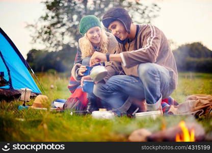 Young camping couple pouring tea