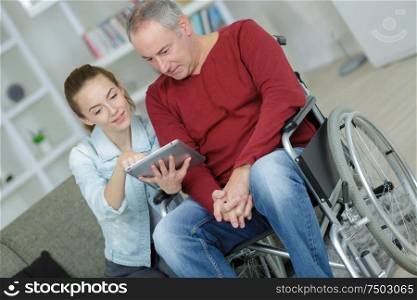 young carer and senior man using tablet