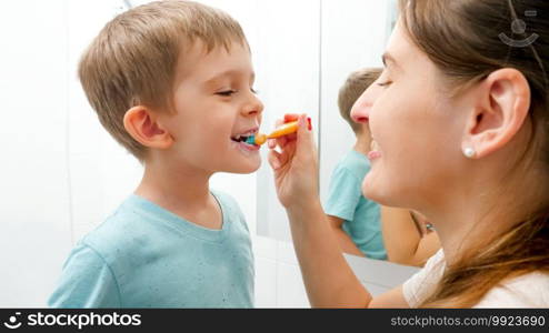 Young caring mother brushing and cleaning teeth of her little son. Parents and children taking care of teeth health and hygiene.. Young caring mother brushing and cleaning teeth of her little son. Parents and children taking care of teeth health and hygiene