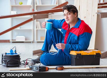 Young carpenter taking break from working with wooden planks