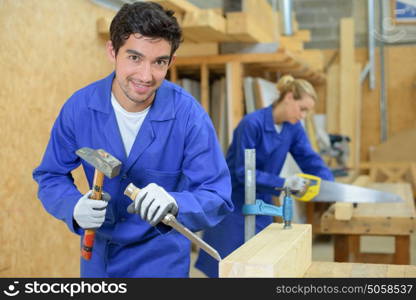 Young carpenter using hammer and chisel